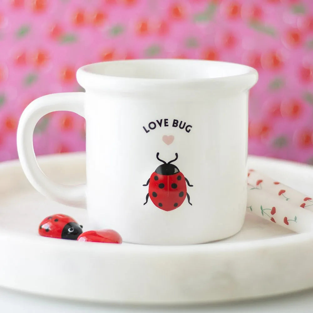 White mug with 'Love Bug' design on a pink floral background