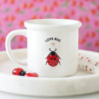 White mug with 'Love Bug' design on a pink floral background