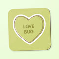 A square coaster with rounded corners in a light olive-green shade, featuring a large heart outline in the center with the words 'LOVE BUG' printed inside. shown on a matching pale green background with a soft drop shadow.