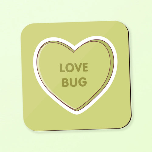 A square coaster with rounded corners in a light olive-green shade, featuring a large heart outline in the center with the words 'LOVE BUG' printed inside. shown on a matching pale green background with a soft drop shadow.