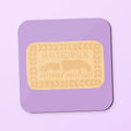 A square coaster featuring a malted milk biscuit on a purple background