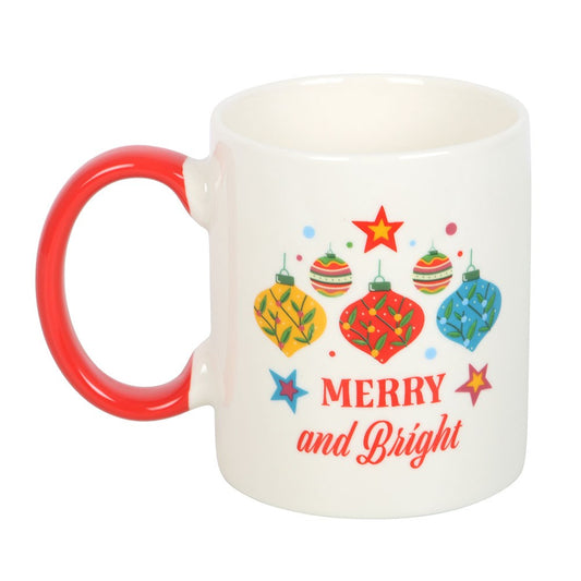 White mug with red handle featuring Christmas-themed design and 'Merry and Bright' text on a white background.