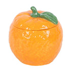 wax candle in a ceramic container shaped like an orange with a green leaf on a white background