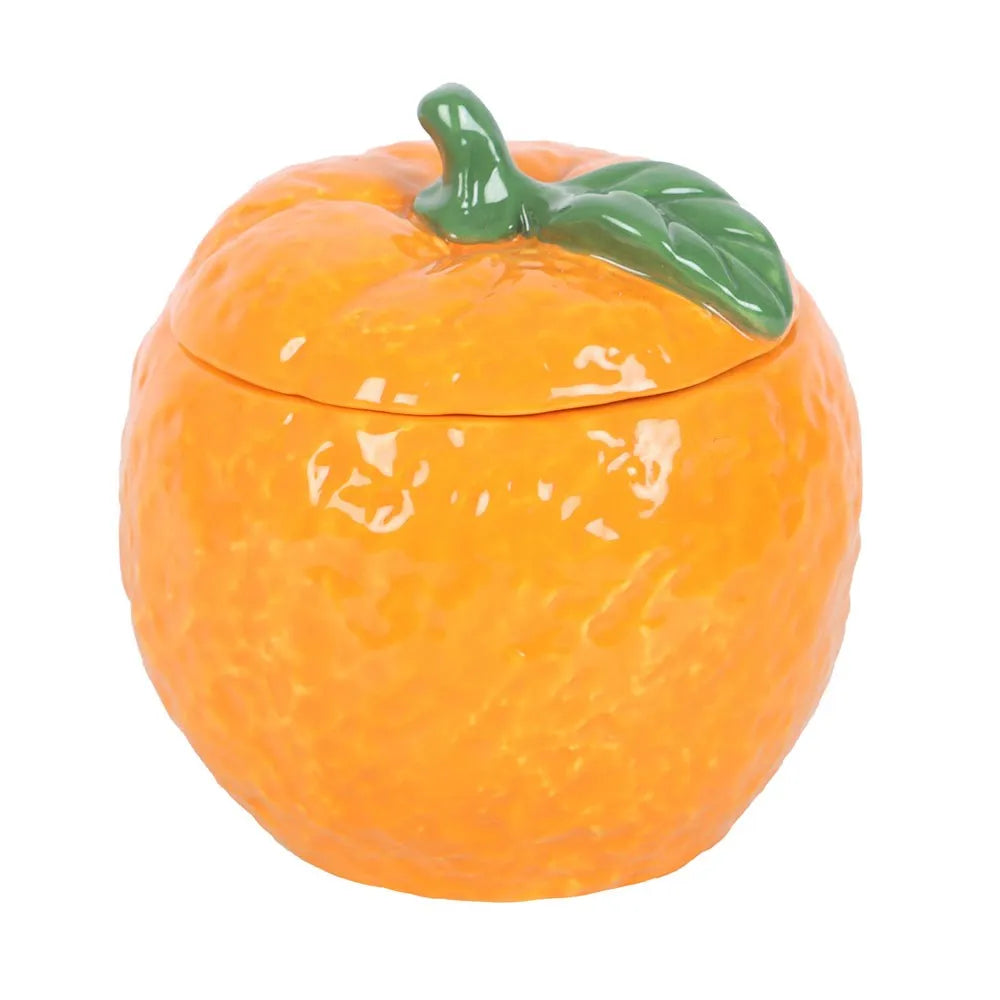 wax candle in a ceramic container shaped like an orange with a green leaf on a white background