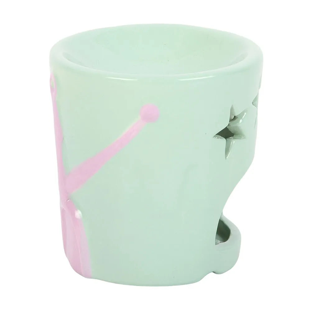 Light green ceramic oil burner with pink handle and star design on a white background