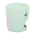 Light green ceramic oil burner with pink handle and star design on a white background