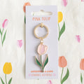 Pink tulip keychain on a branded card with floral design