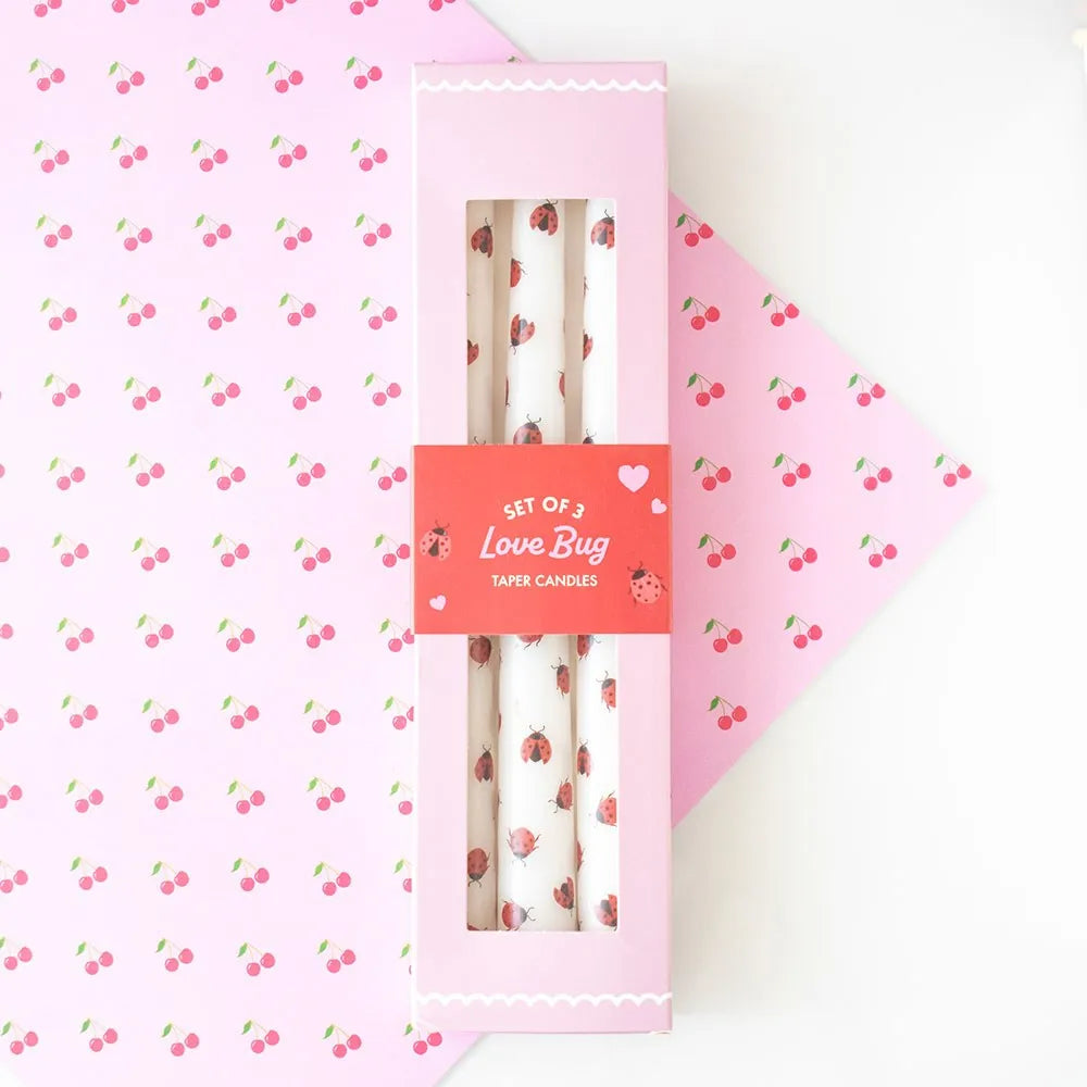 Set of three Love Bug taper candles in a pink box on a pink background with cherry pattern