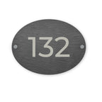 Slate oval house number sign with '132' on a white background