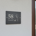 slate sign House number 58 sign on a grey wall next to a brown door.