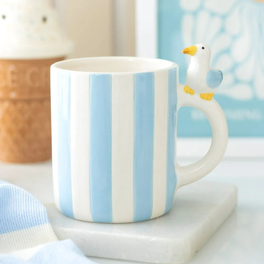 Striped mug with a seagull-shaped handle on a light surface