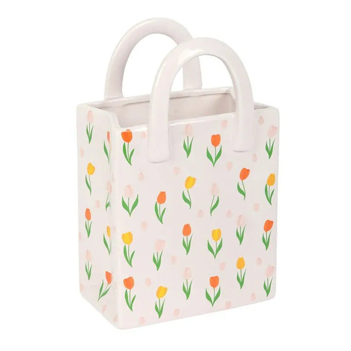 Small rectangular bag vase with floral pattern and white handles on a white background
