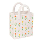 Small rectangular bag vase with floral pattern and white handles on a white background