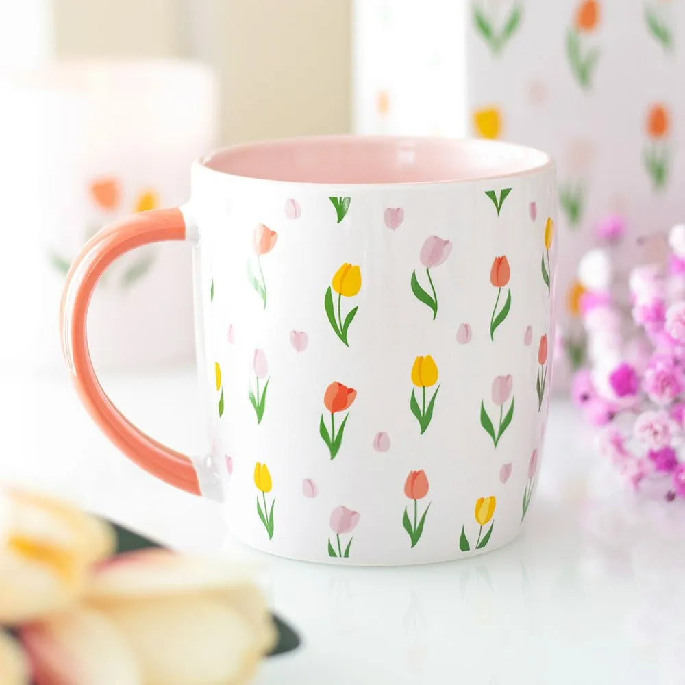 White mug with floral pattern and pink handle on a blurred background