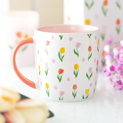 White mug with floral pattern and pink handle on a blurred background