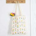 Tote bag with tulip pattern and flowers hanging on a wooden hook.