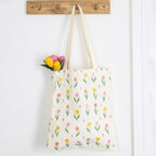 Tote bag with tulip pattern and flowers hanging on a wooden hook.