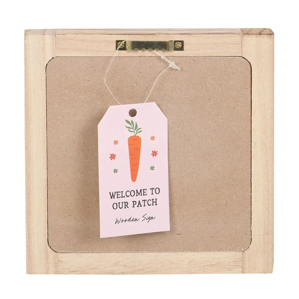 Wooden sign with a 'Welcome to Our Patch' tag featuring a carrot illustration.