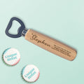Personalized wooden bottle opener with engraved name and message on a light mint background, with two decorative 'Unique Street' bottle tops
